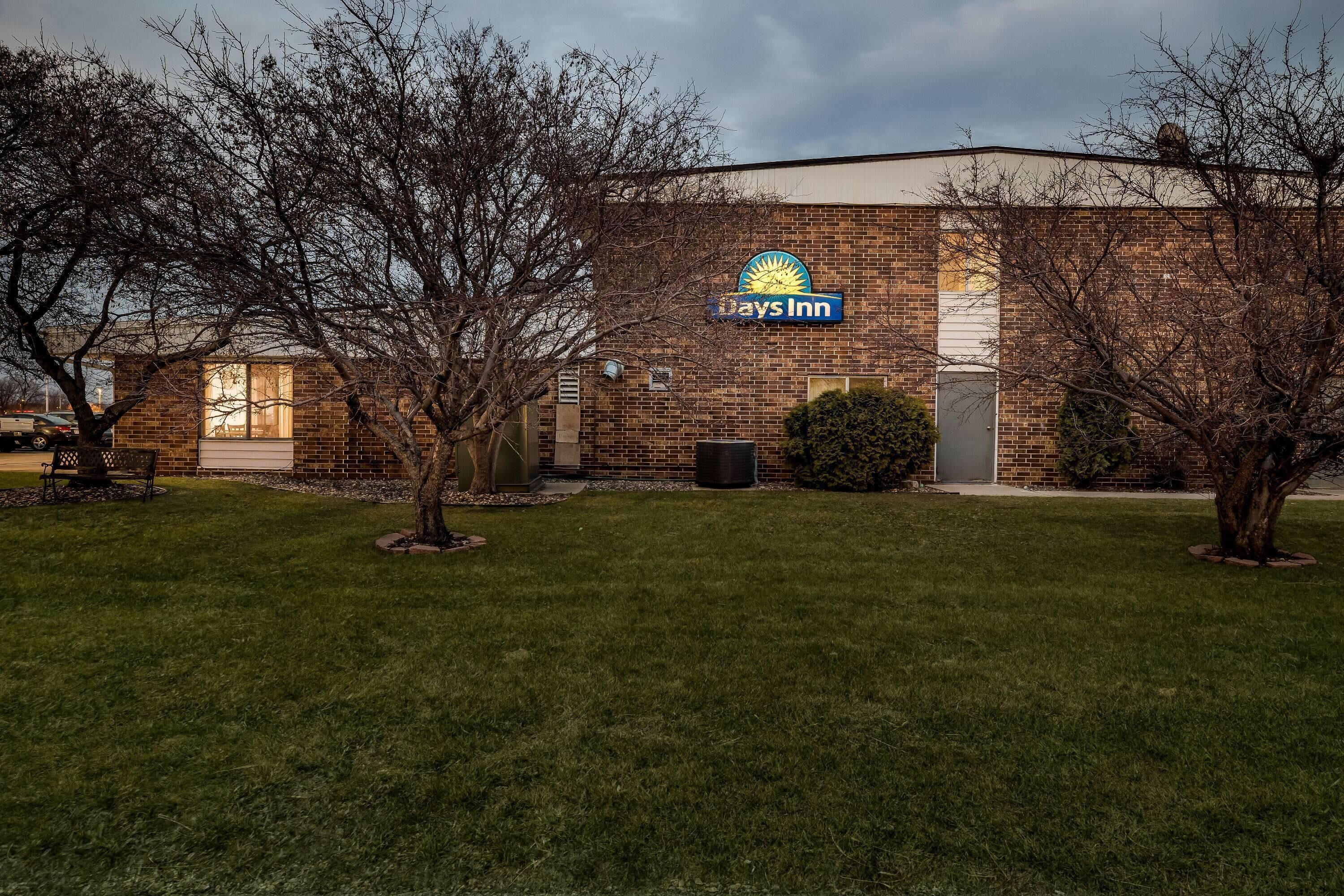 A brick building with a 'Days Inn' sign, a grassy lawn, and leafless trees.