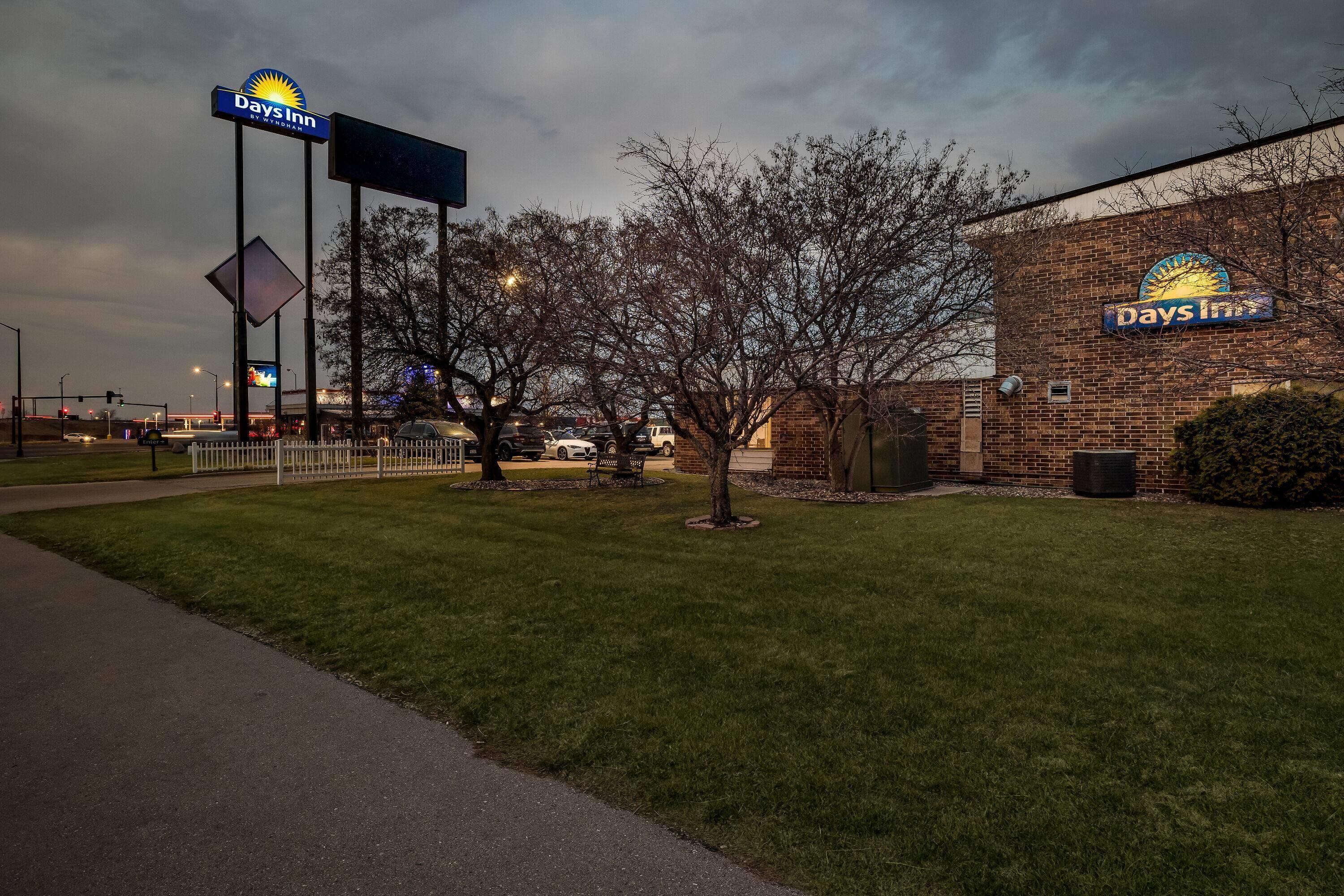 A Days Inn hotel with a brick facade, a large illuminated sign, and a well-maintained lawn.
