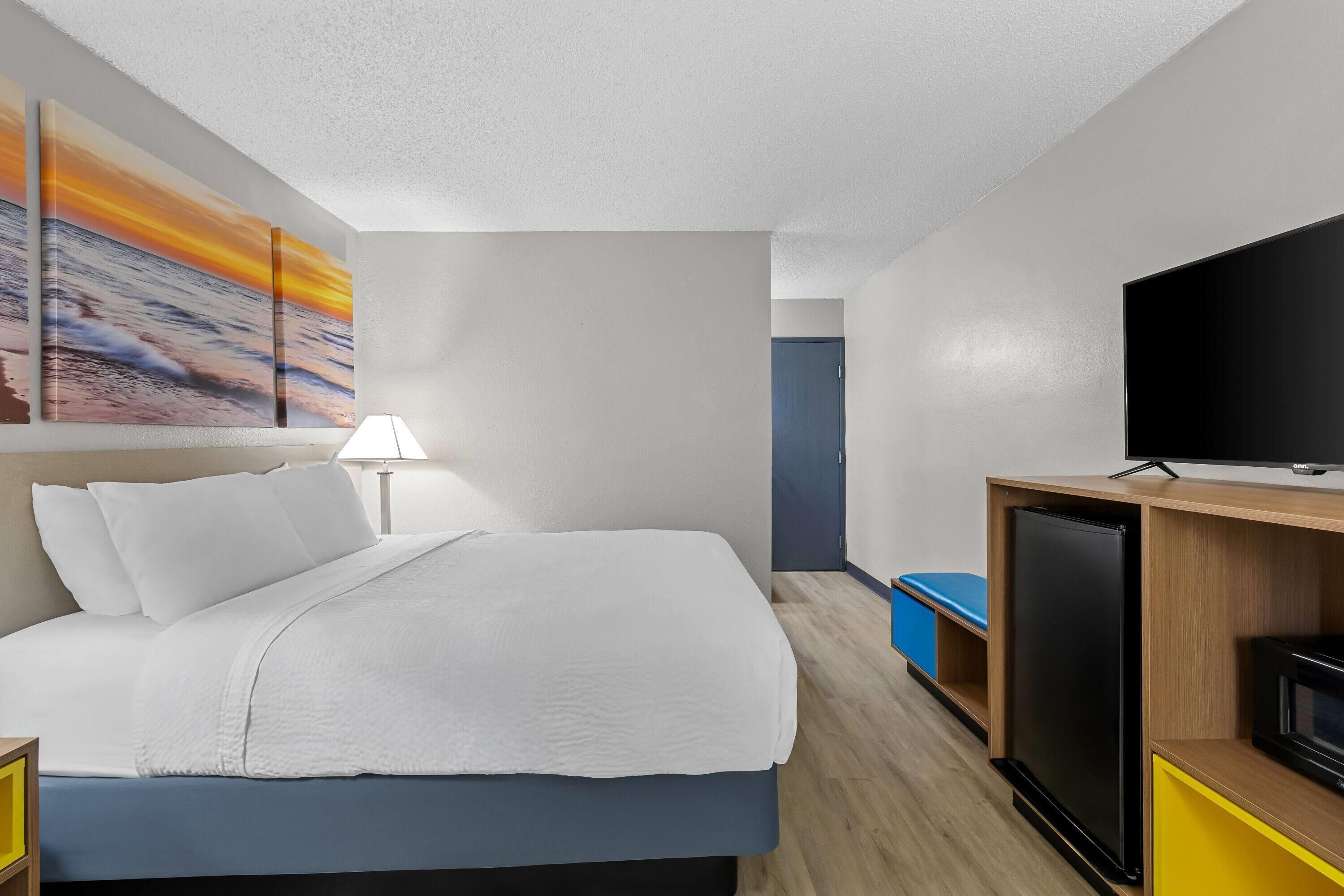 Une chambre d’hôtel équipée d’un lit, d’une télévision, d’un bureau et d’un réfrigérateur.