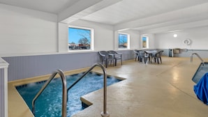 A pool area with a hot tub, a table with chairs, and a view of the outside. - Days Inn by Wyndham Fond du Lac (Fond du Lac)