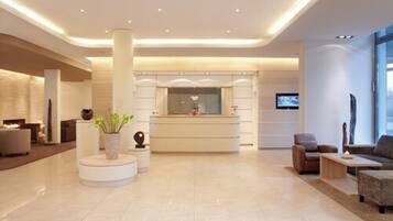 Una moderna hall d'albergo con reception, area salotto e camino.