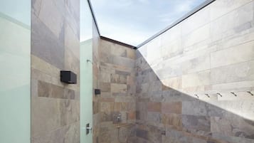 Um chuveiro moderno com azulejos de pedra e porta de vidro.