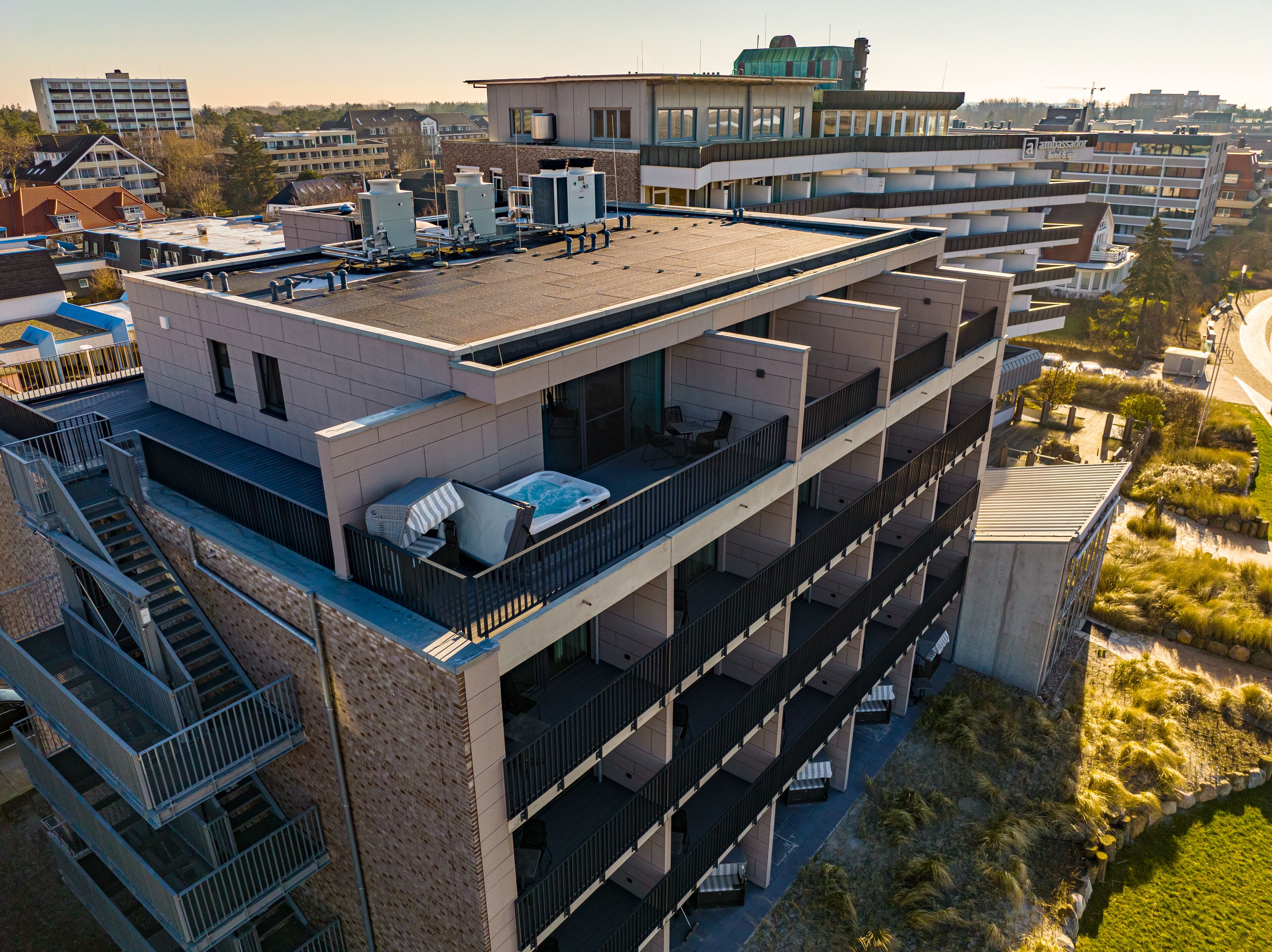 A multi-story building with balconies, a rooftop pool, and a view of the surrounding area.