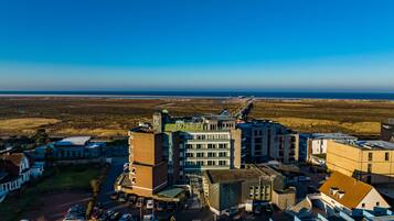 A hotel complex with multiple buildings, parking areas, and a view of the beach.