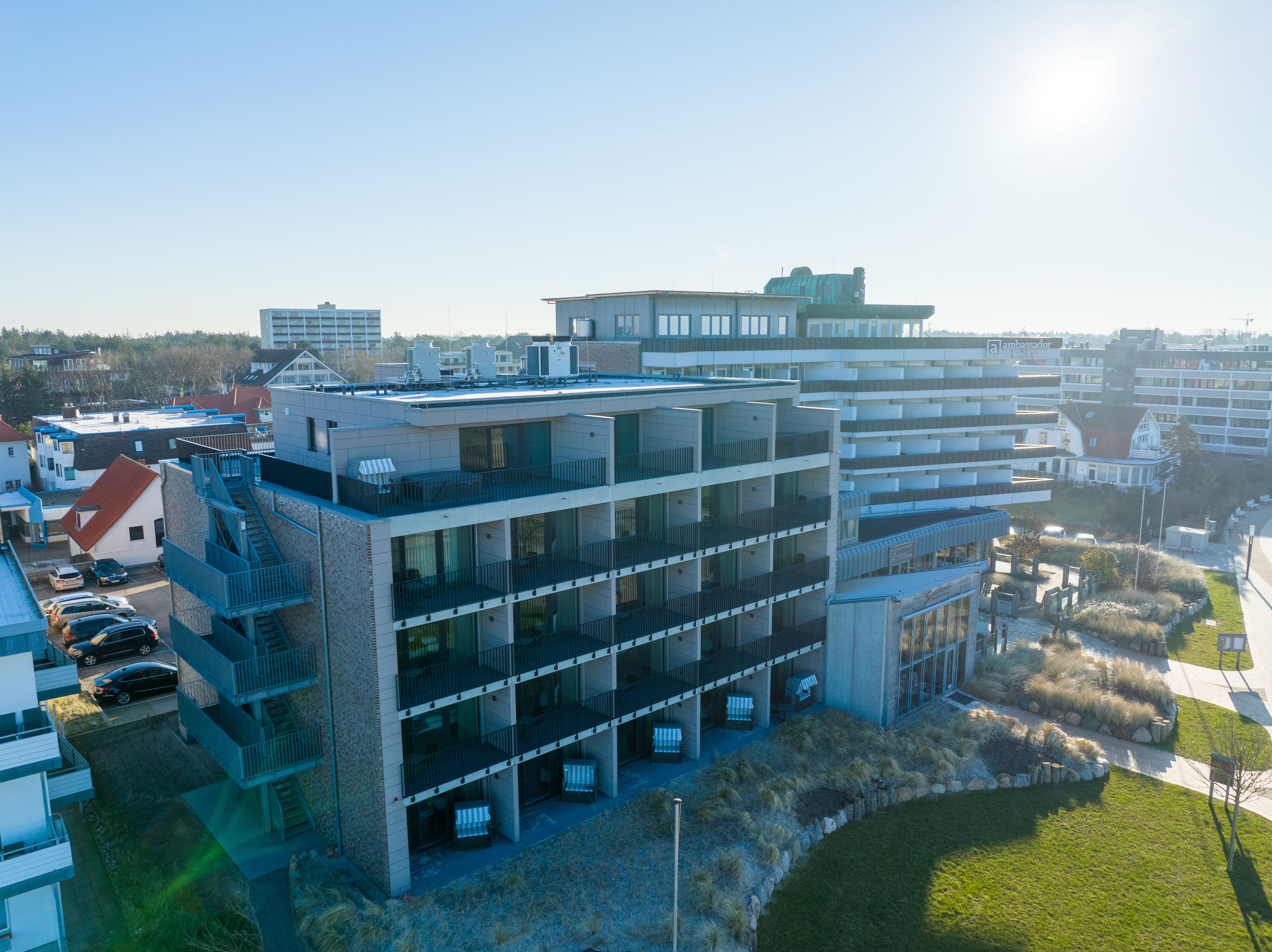 Een hotel met meerdere verdiepingen, balkons, een parkeerplaats en een aangelegde tuin.