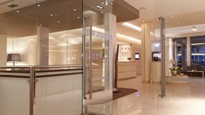 Un moderno vestíbulo de hotel con separadores de vidrio, una recepción y una zona de estar.