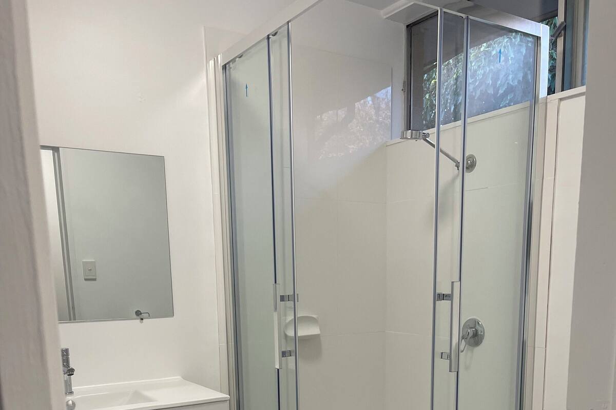 A modern bathroom with a glass-enclosed shower, a white vanity with drawers, and a toilet.