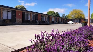Situated in a parking lot, this motel features rooms with large windows and a stone facade.