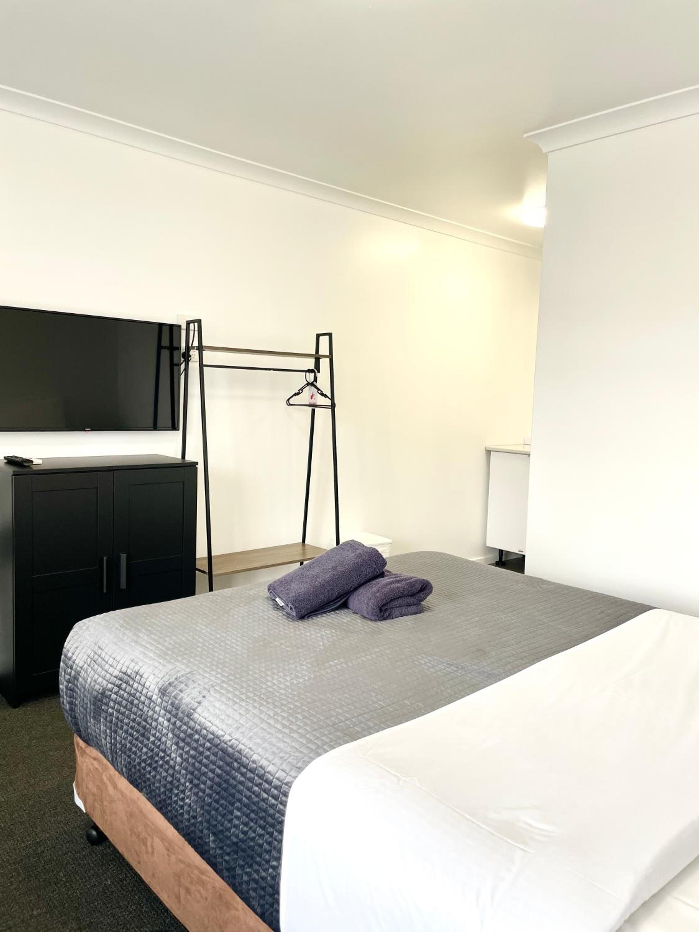 A hotel room with a bed, a desk, a chair, and a TV.