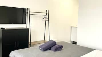 A hotel room with a bed, a desk, a chair, and a TV.