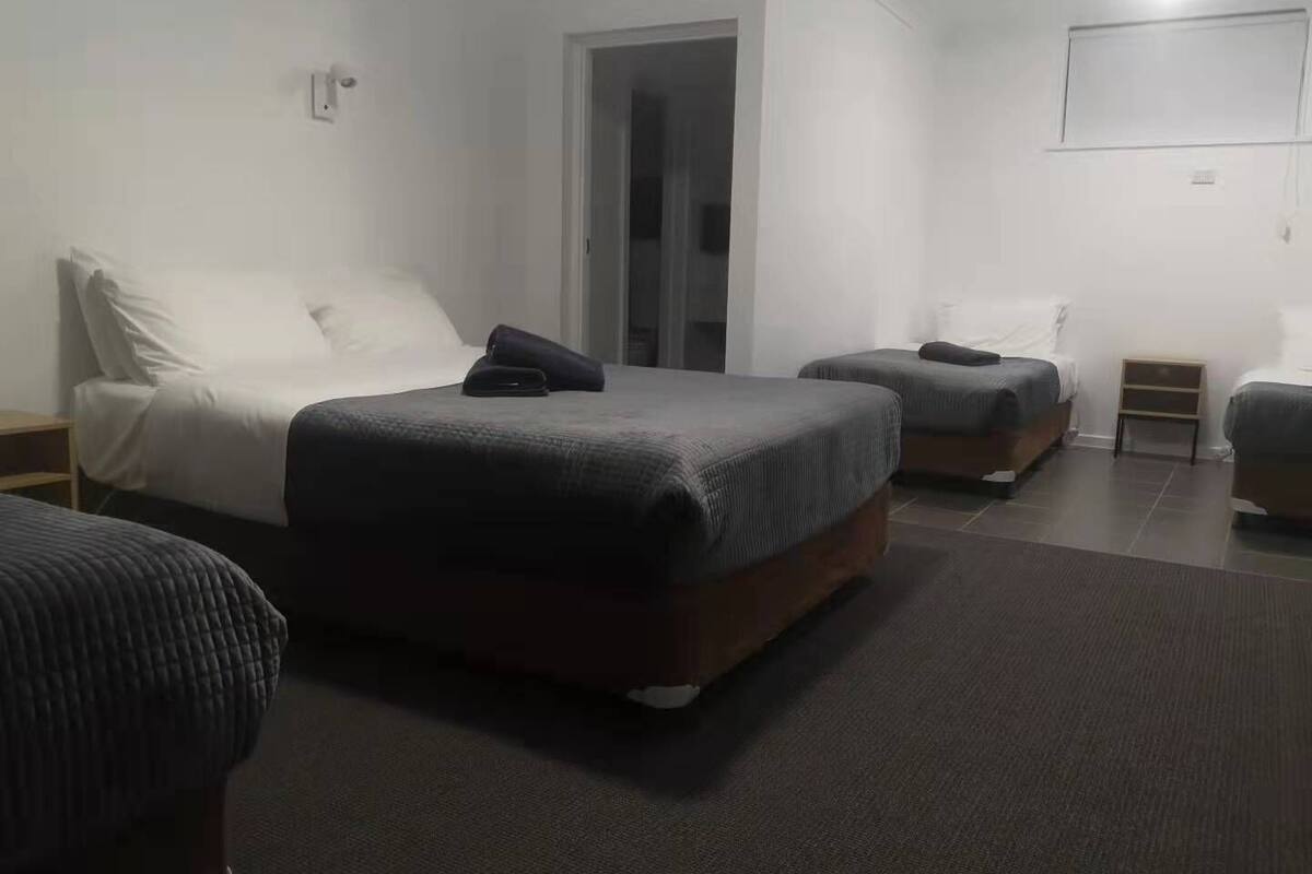 A hotel room with two beds, a small table, and a TV mounted on the wall.