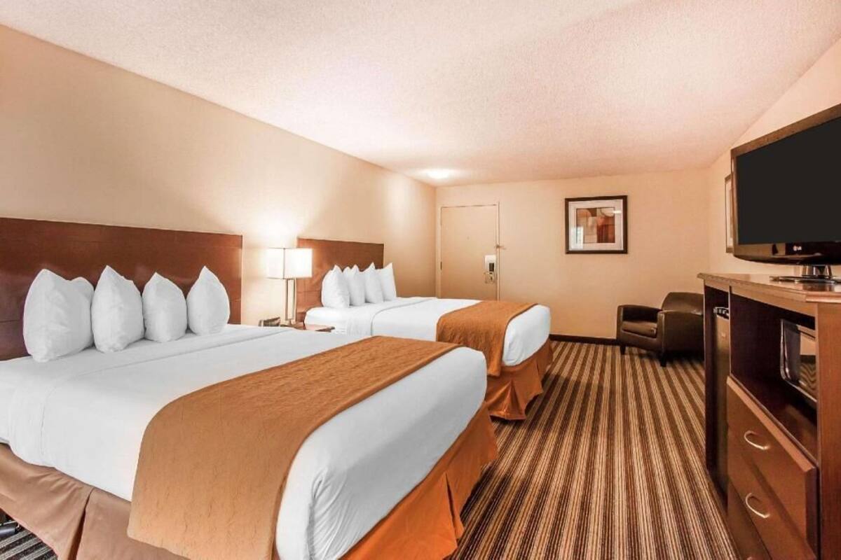 A hotel room with two beds, a TV, a desk, and a chair.