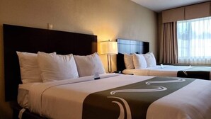 A hotel room with two beds, each with white bedding and a dark headboard. There is a window with curtains on the right side. - Quality Inn & Suites Vancouver - Hazel Dell (Vancouver)