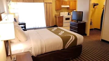 Habitació d'hotel amb llit, televisió, petita cuina i bany.
