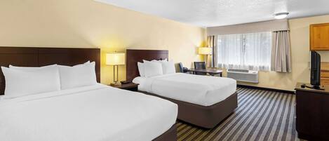 A hotel room with two beds, a desk, a chair, a TV, and a window with curtains.
