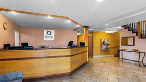 A hotel reception area with a wooden reception desk, a clock, and a sign that reads "Quality by Choice Hotels". - Quality Inn & Suites Vancouver - Hazel Dell (Vancouver)