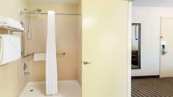 A hotel bathroom with a shower, a towel rack, and a door leading to another room.
