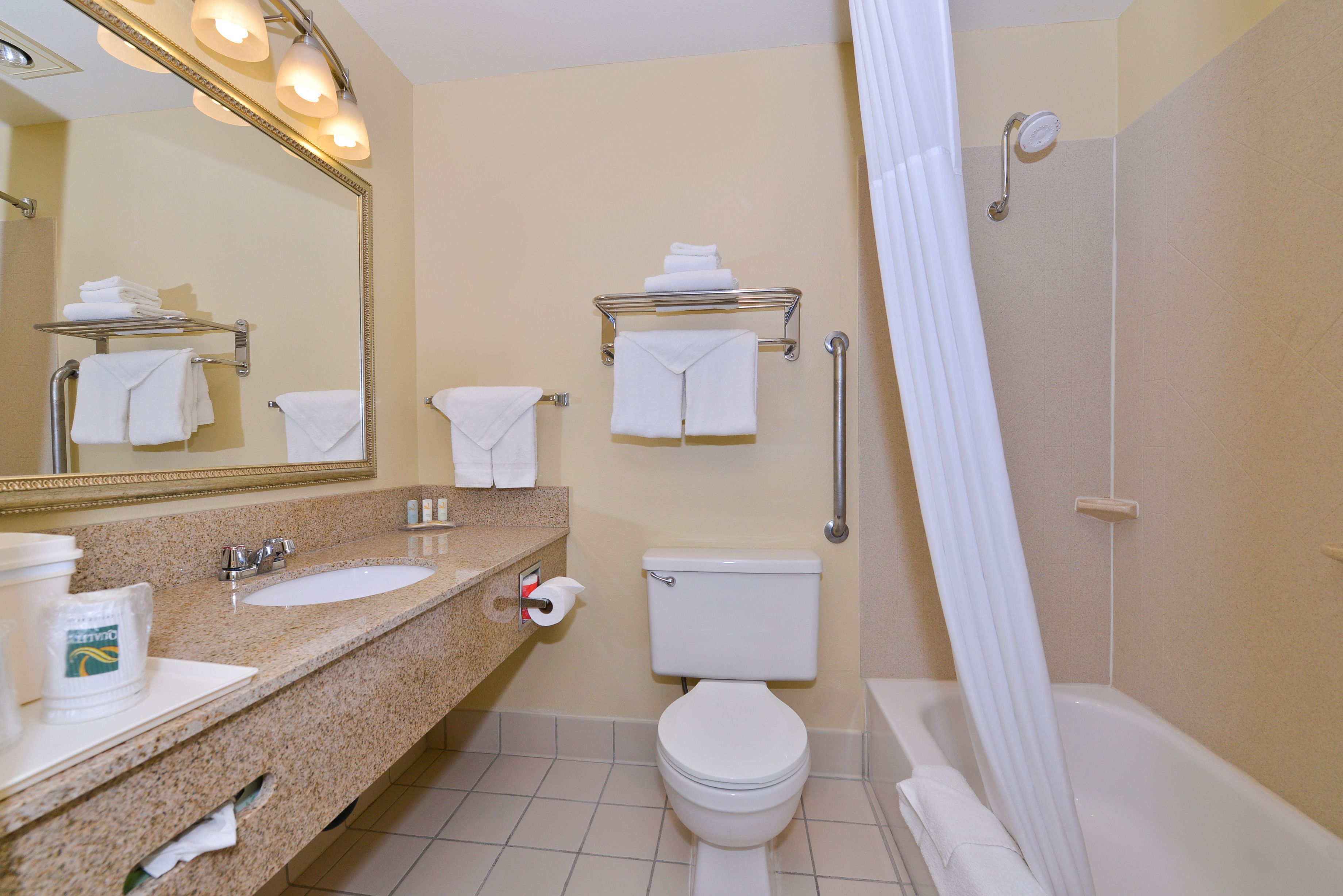 A bathroom with a sink, toilet, and shower. There are towels and a mirror.