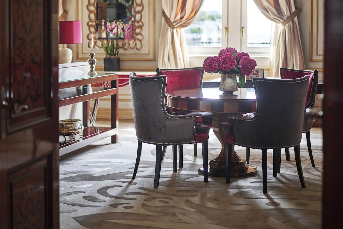 A dining area with a round table, four chairs, and a vase of flowers.