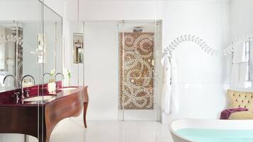 Een moderne badkamer met een grote spiegel, een wastafel met donkerhouten afwerking, een vrijstaand bad en een douchecabine met glazen wanden.