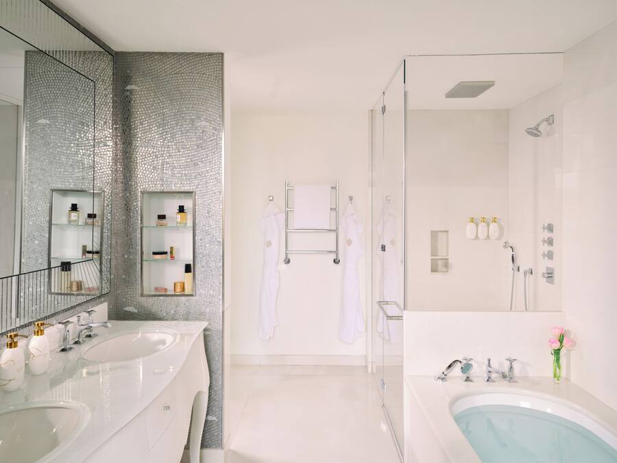 A modern bathroom with two sinks, a glass shower enclosure, and a large mirror.