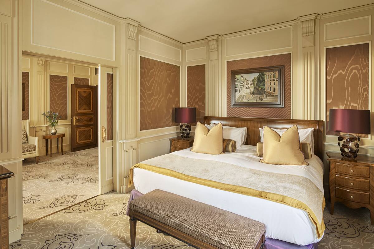 A spacious bedroom with a large bed, wooden headboard, and a bench.