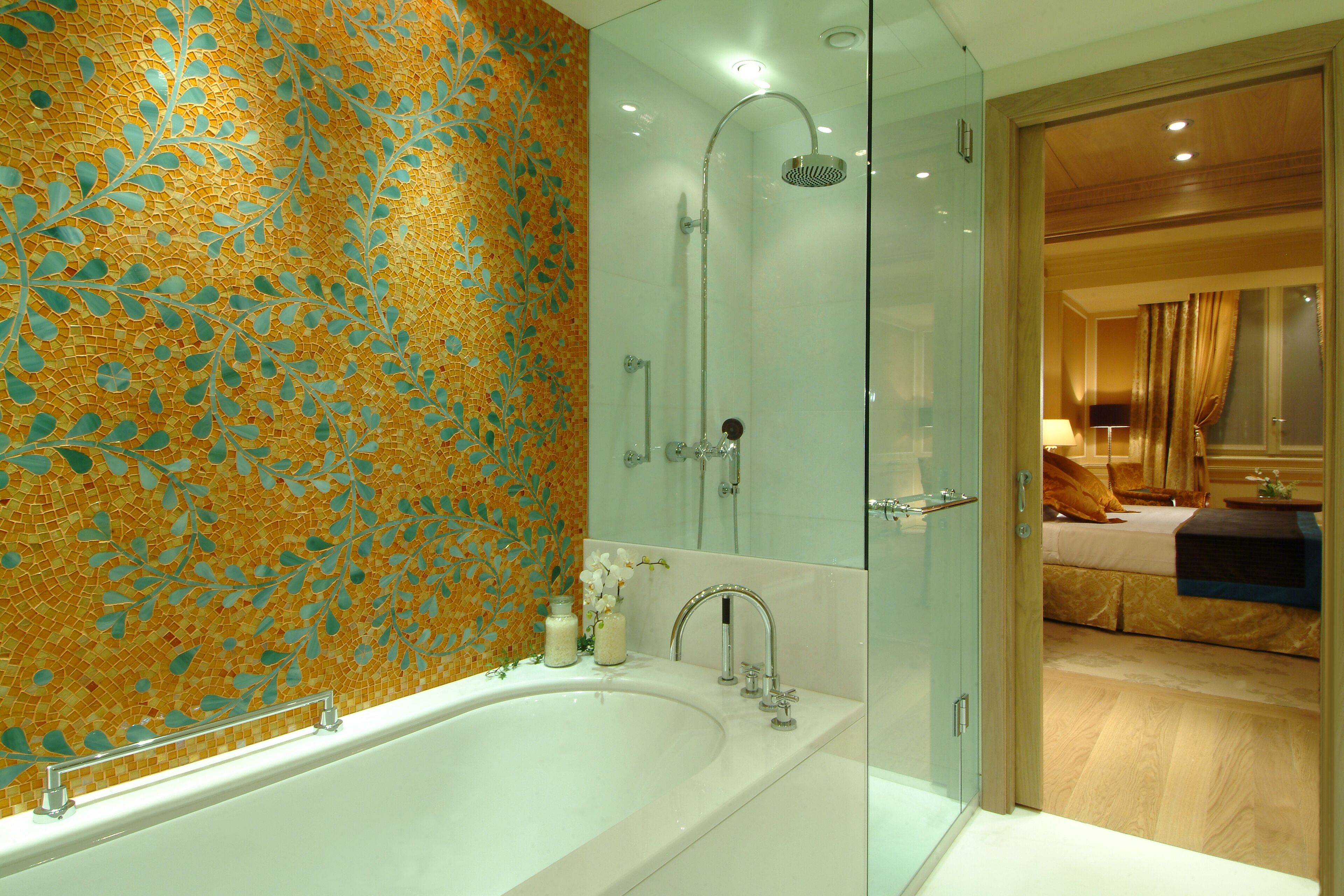 Un bagno moderno con una vasca da bagno ampia, una doccia vetrata e un pannello decorativo in mosaico.