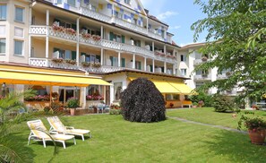 A hotel with multiple balconies, a well-maintained lawn, and outdoor seating. - Wittelsbacher Hof Swiss Quality Hotel (Garmisch-Partenkirchen)