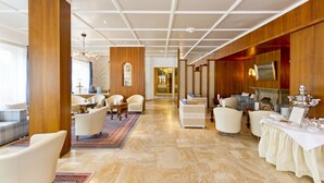 A hotel lobby with a central corridor, seating areas, a fireplace, and a buffet setup.