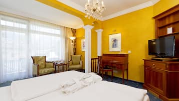 Een hotelkamer met een groot bed, een bureau, een televisie en een kroonluchter.