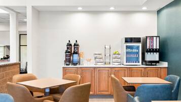 Un café moderno con mostrador, máquinas de café, dispensador de agua y refrigerador.