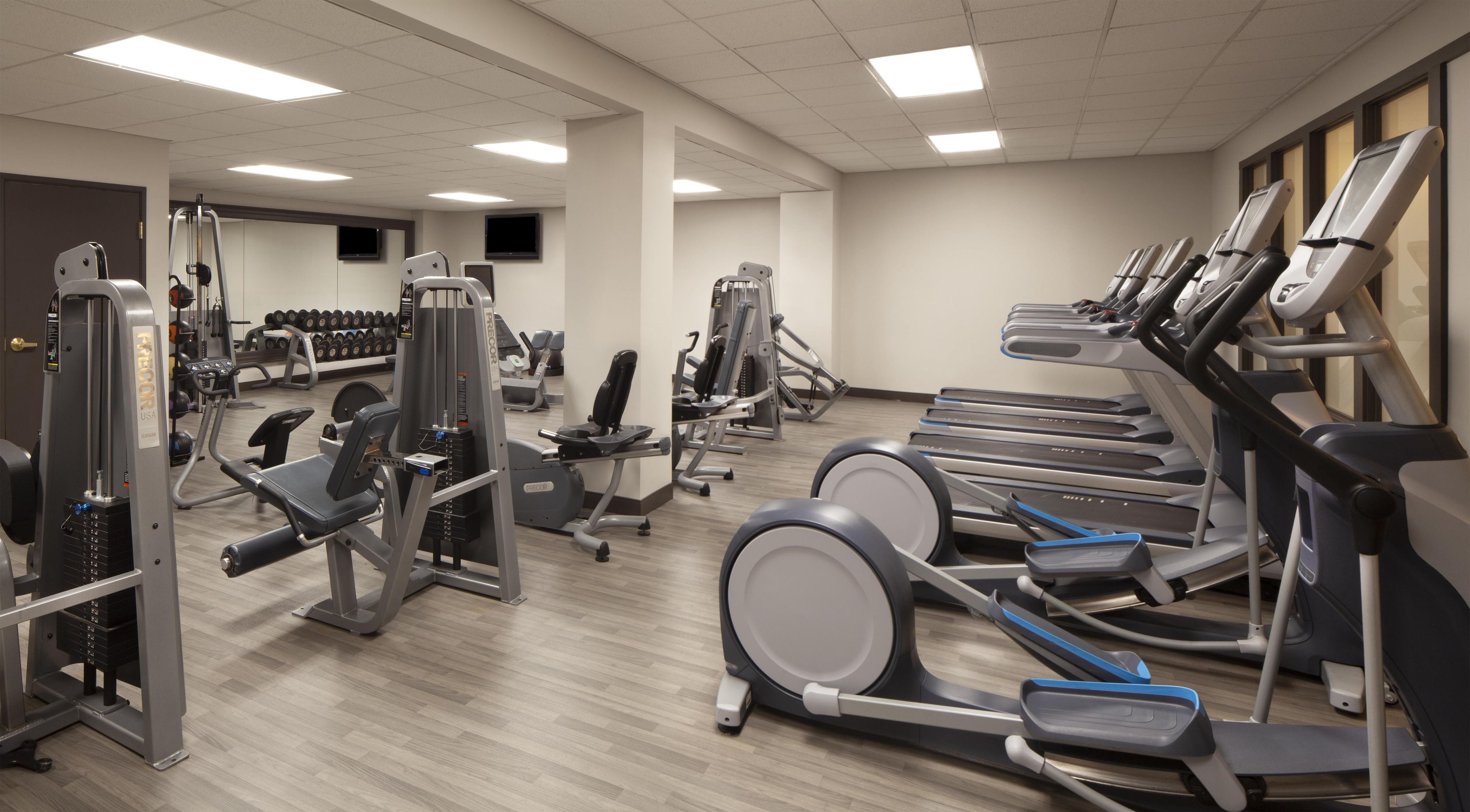 Ein Fitnessstudio mit Laufbändern, Kraftgeräten und Kurzhanteln.