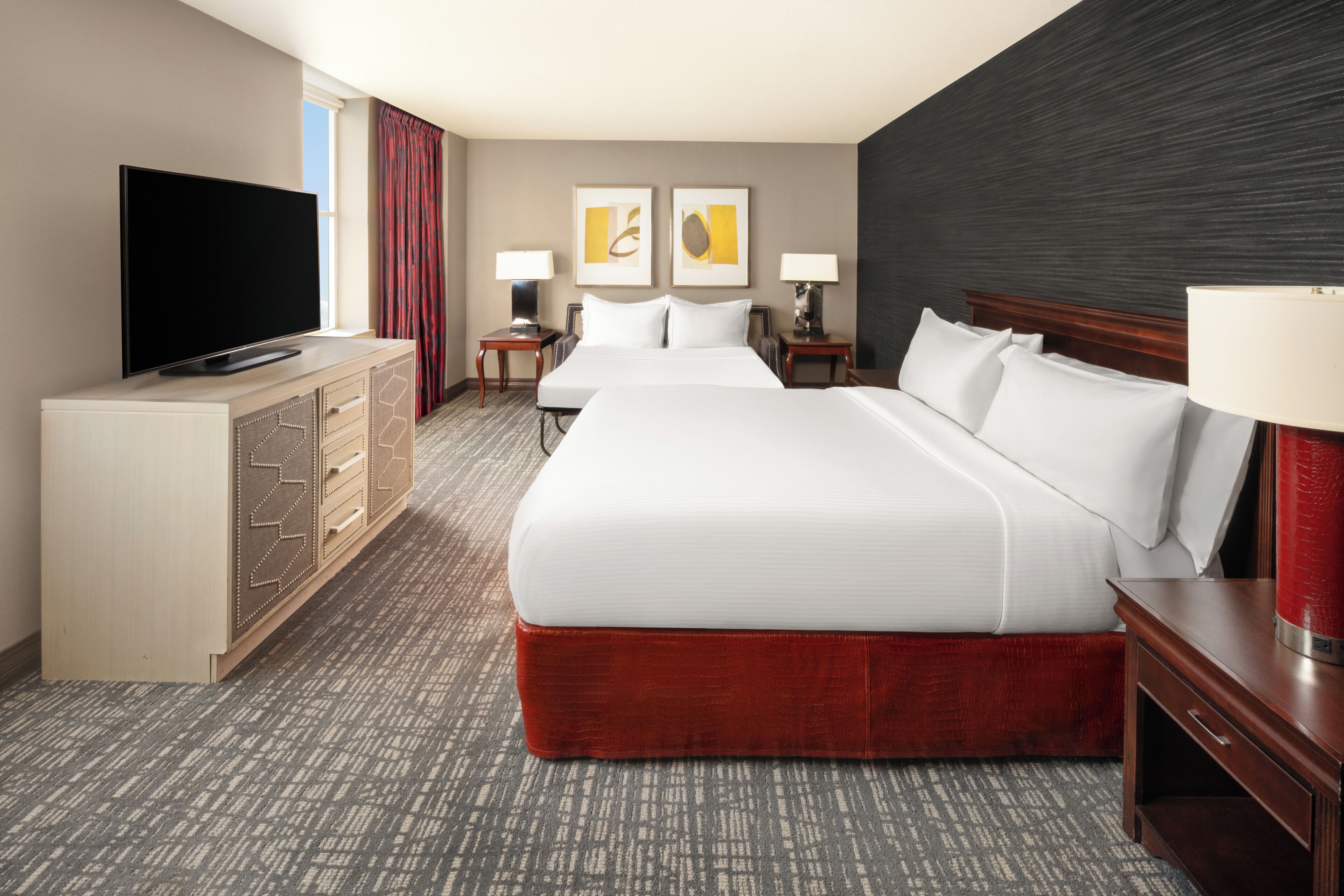Een hotelkamer met een groot bed, een televisie, een bureau en een dressoir.