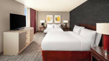 Een hotelkamer met een groot bed, een televisie, een bureau en een dressoir.