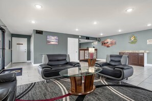 A hotel lobby with two black leather sofas, a glass coffee table, and a reception desk.