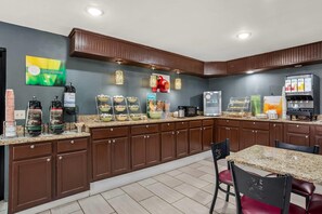 A modern kitchen with a granite countertop, built-in cabinets, a coffee station, and a refrigerator.