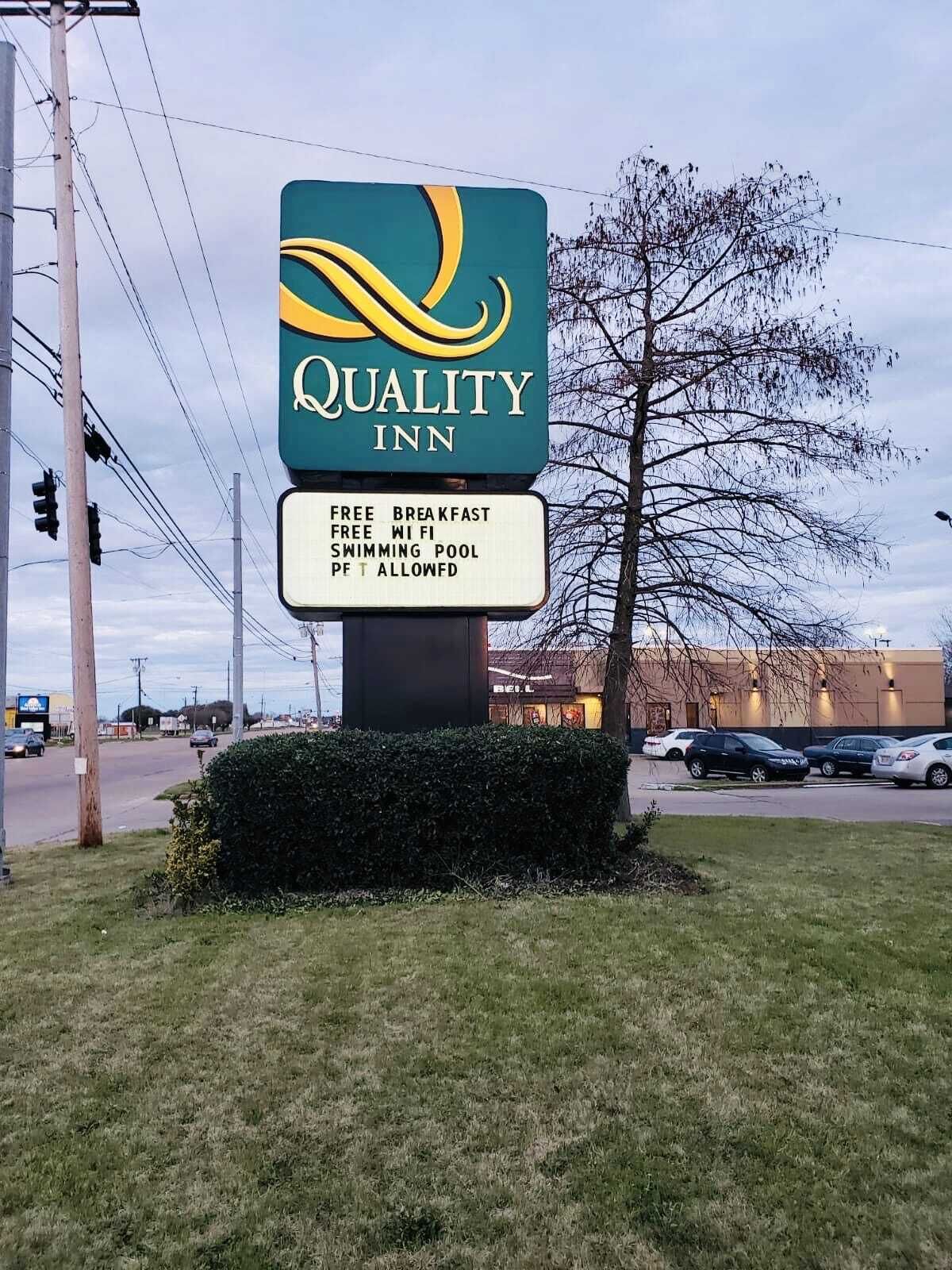 Letrero de Quality Inn con los servicios indicados: desayuno gratuito, WiFi gratuito, piscina y admitimos mascotas.
