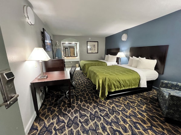 Une chambre d’hôtel avec deux lits, un bureau, une chaise et une salle de bain.