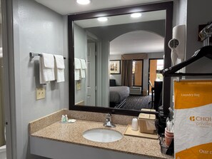 A hotel bathroom with a sink, mirror, towel rack, and a hairdryer.
