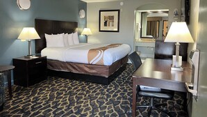 Habitación de hotel con cama, dos lámparas de noche, escritorio con silla, espejo y alfombra estampada.