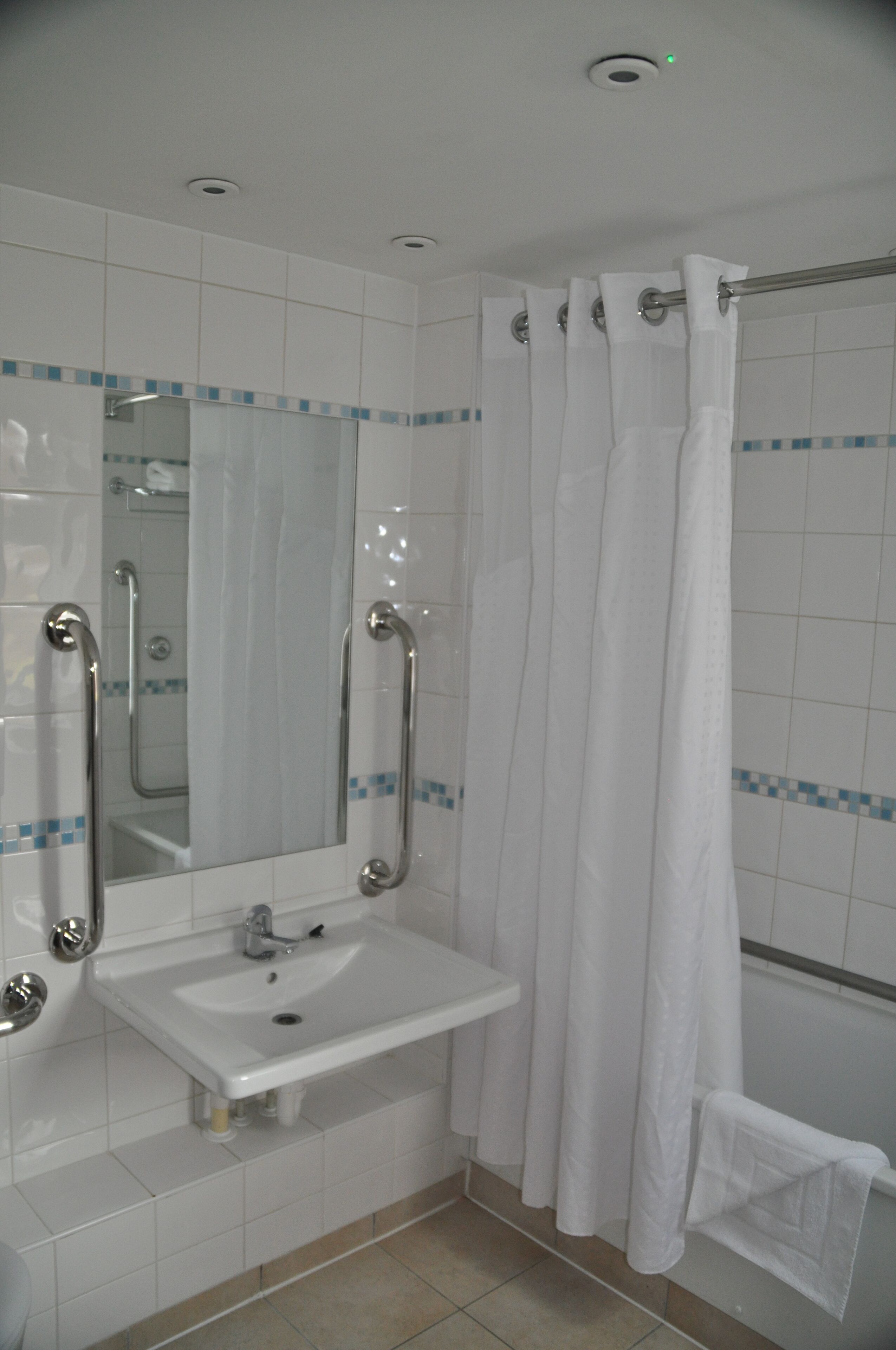 Une salle de bain avec un lavabo blanc, un miroir et un rideau de douche.