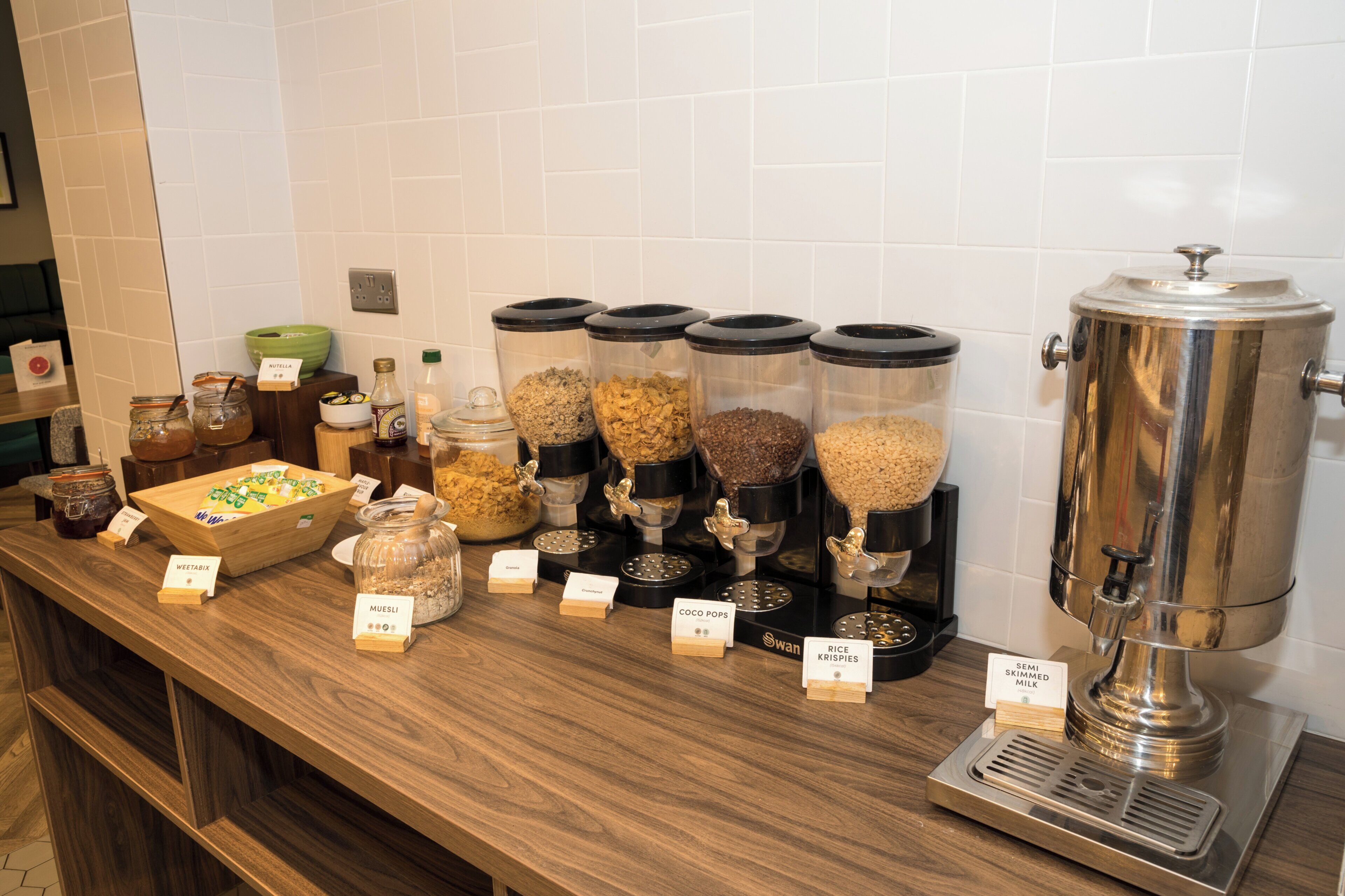 Uma área de buffet com diversos distribuidores de alimentos e uma máquina de café.