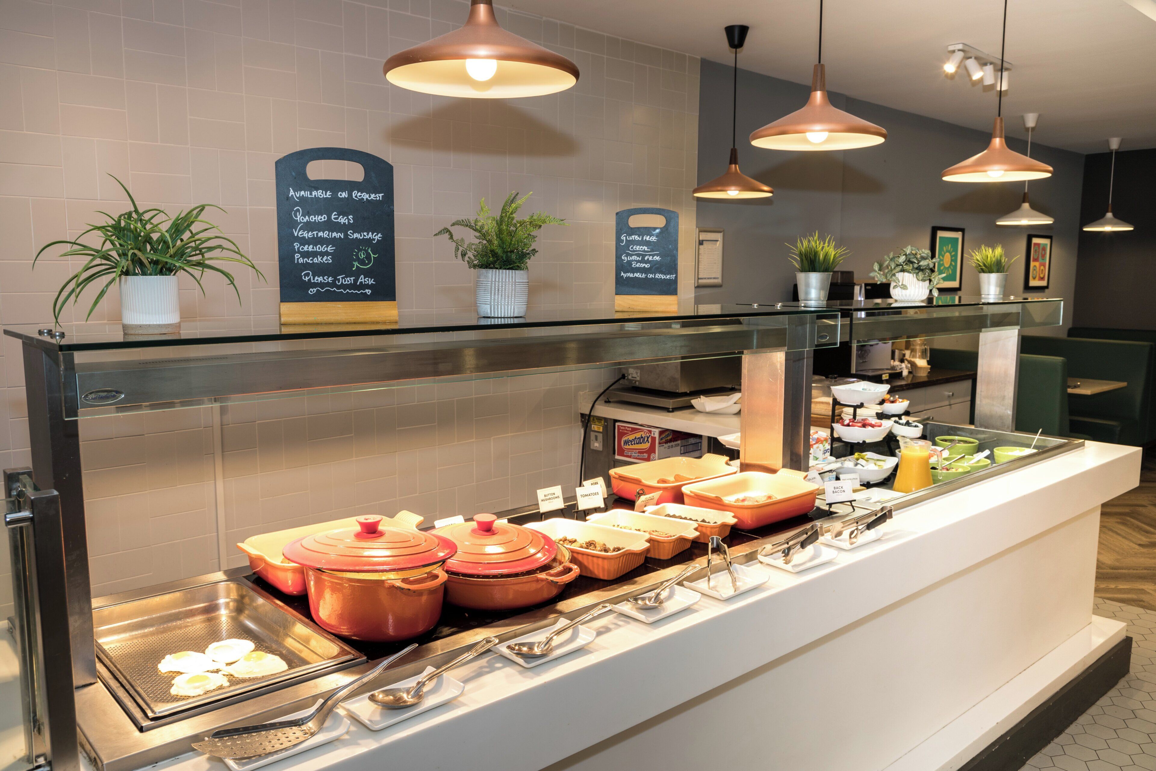 Zona de buffet con diferentes opciones de comida y un cartel que indica opciones sin gluten.