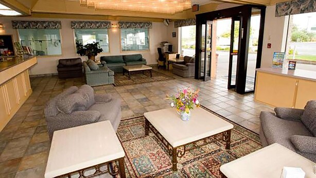Un vestíbulo amplio con mostrador de recepción, sofás, una mesa de centro y un ventanal con vistas al exterior.