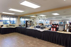 A buffet setup with a long table, food items, and a refrigerator.