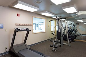A gym with a treadmill, weight machines, and a mirror.