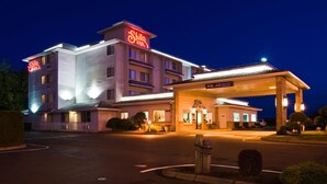 Un hotel con un llamativo letrero de 'Shilo Inn', un acceso cubierto al vestíbulo y un estacionamiento.