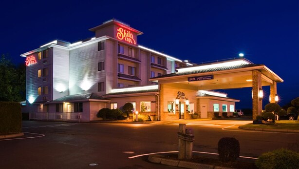 A hotel with a prominent 'Shilo Inn' sign, a covered lobby entrance, and a parking lot. - Shilo Inn Suites Warrenton (Warrenton)