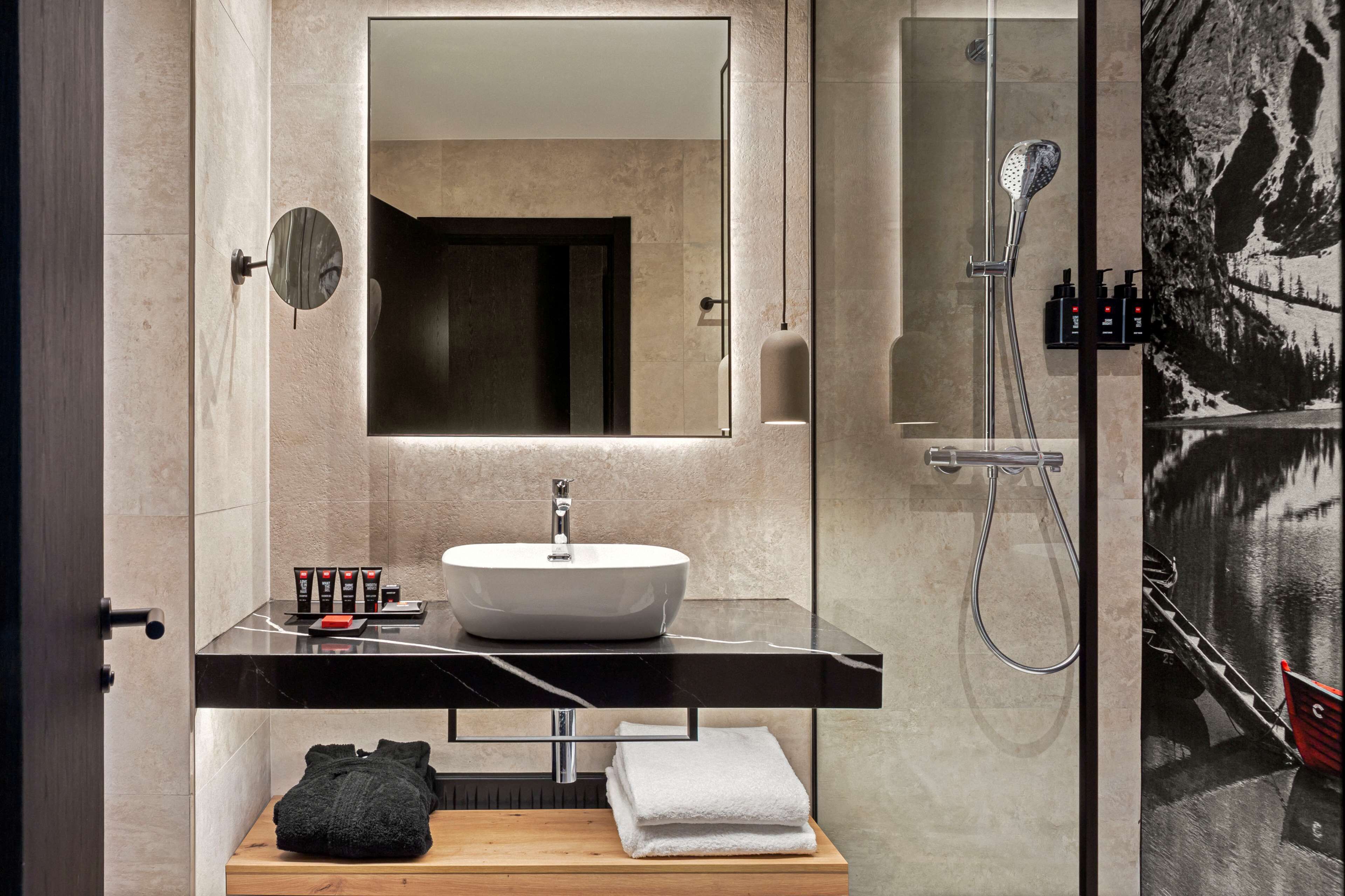 Un baño moderno con un espejo grande, un lavabo blanco y una ducha.