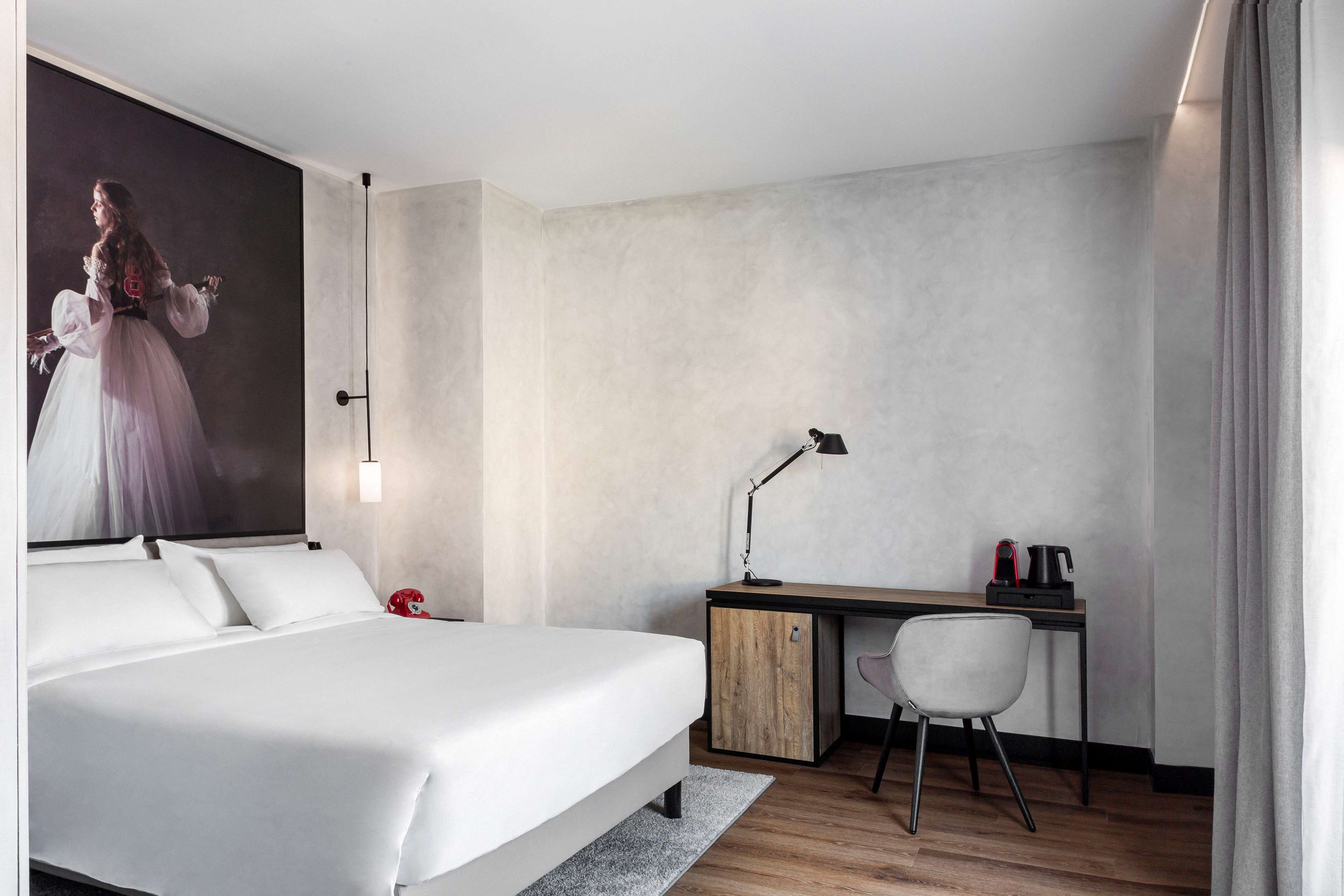 A modern hotel room with a large bed, a desk, and a chair.